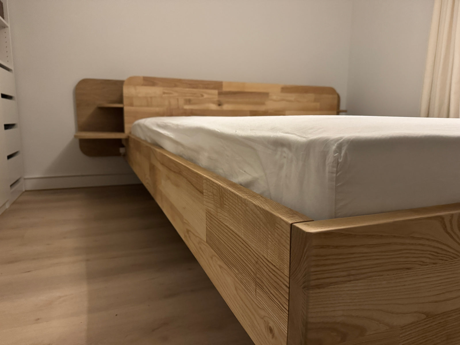 Op maat gemaakt bedframe van eikenhout met ingebouwde nachtkastjes.