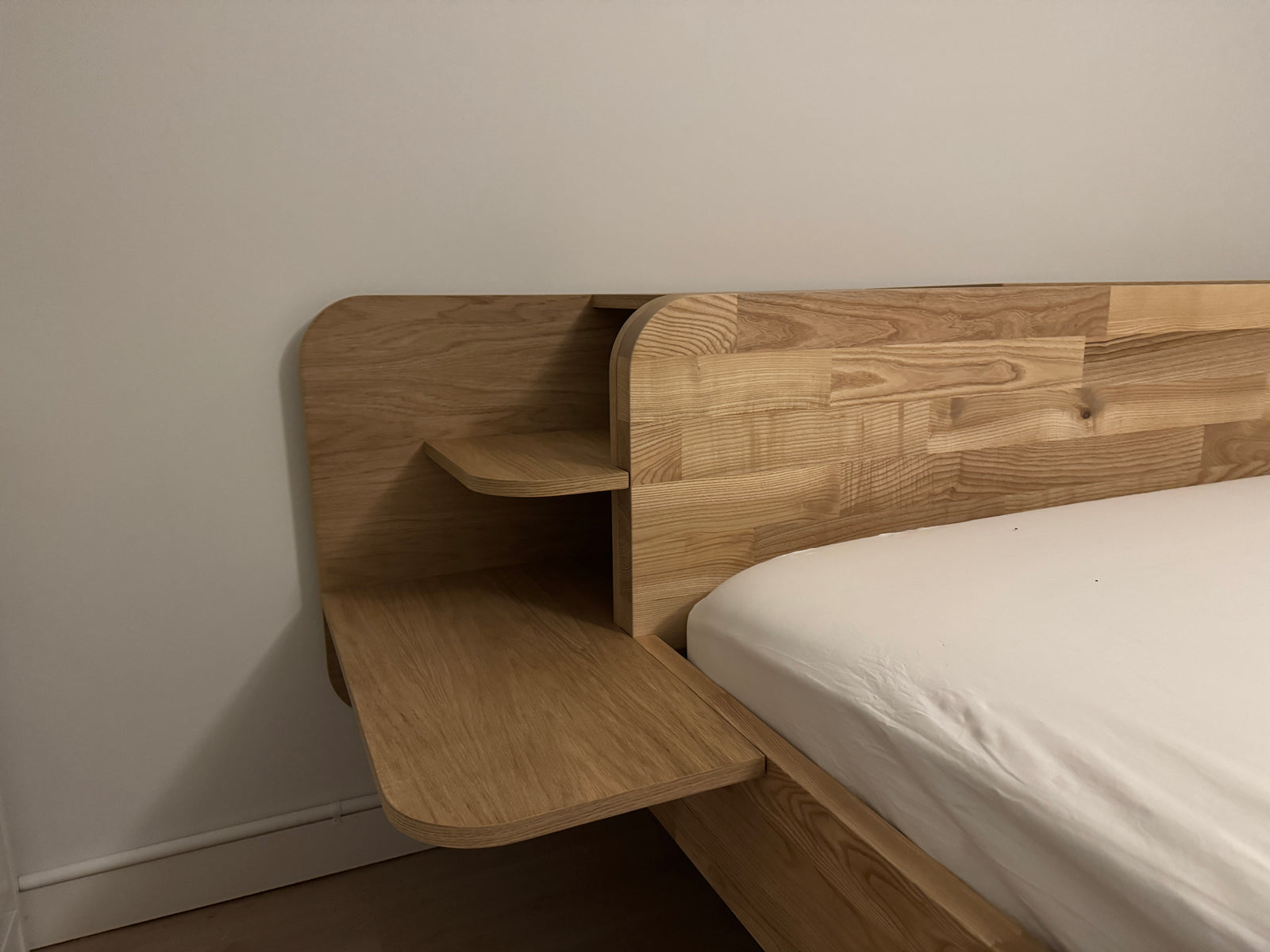 Op maat gemaakt bedframe van eikenhout met ingebouwde nachtkastjes.